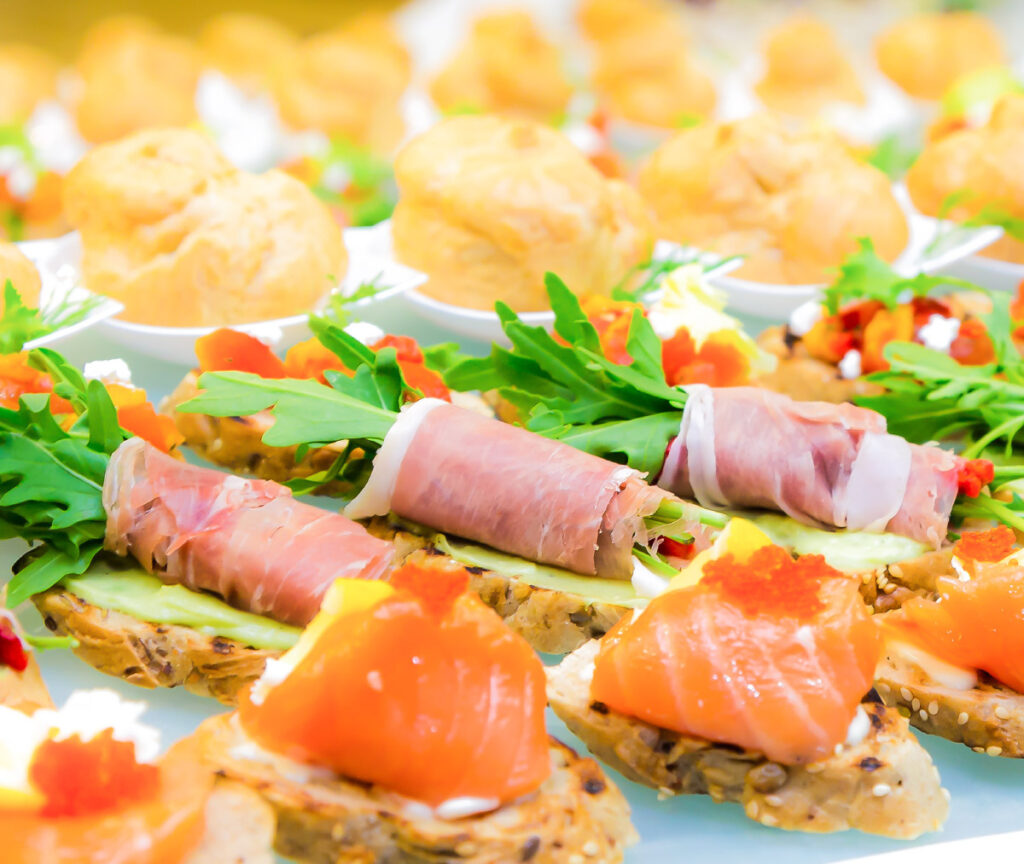 Vielfältige Fingerfood-Platte mit belegten Häppchen, Lachs, Schinken, Rucola und kleinen herzhaften Gebäckstück